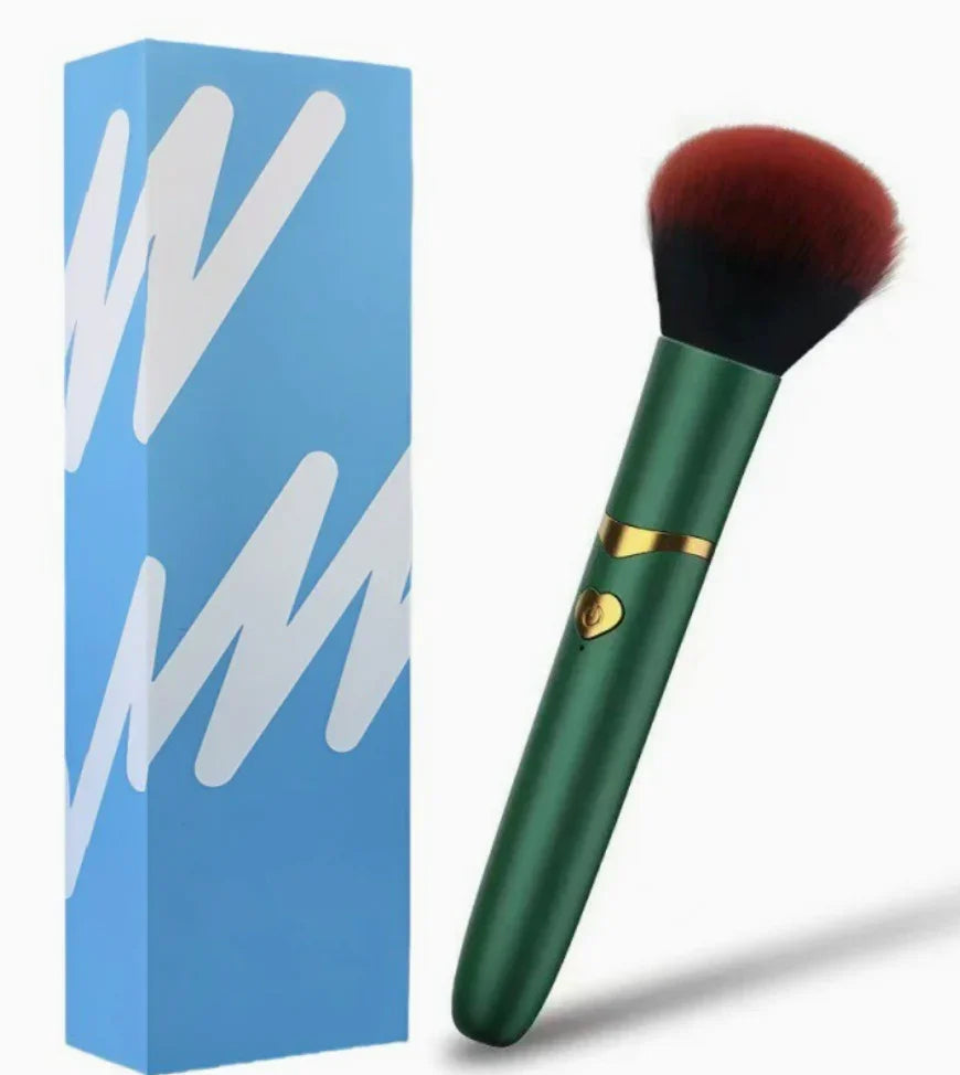 Green and gold makeup brush with fluffy red bristles beside a blue gift box