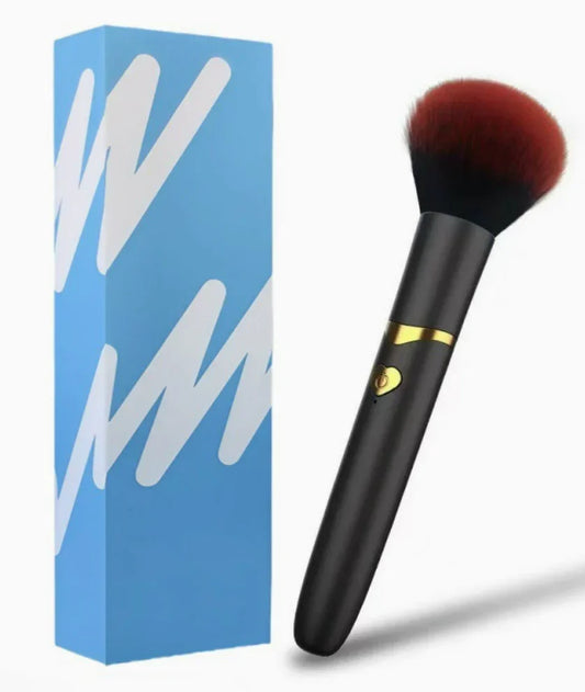 Black and gold makeup brush with red bristles beside a blue and white box on white background